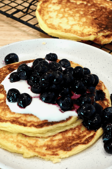 Protein pancakes with yogurt and blueberries on a plate.