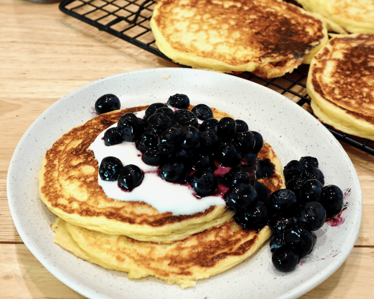 Protein pancakes with yogurt and blueberries on a plate.