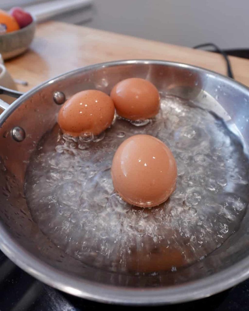 3 eggs in a pot, cooking in a small amount of boiling water.