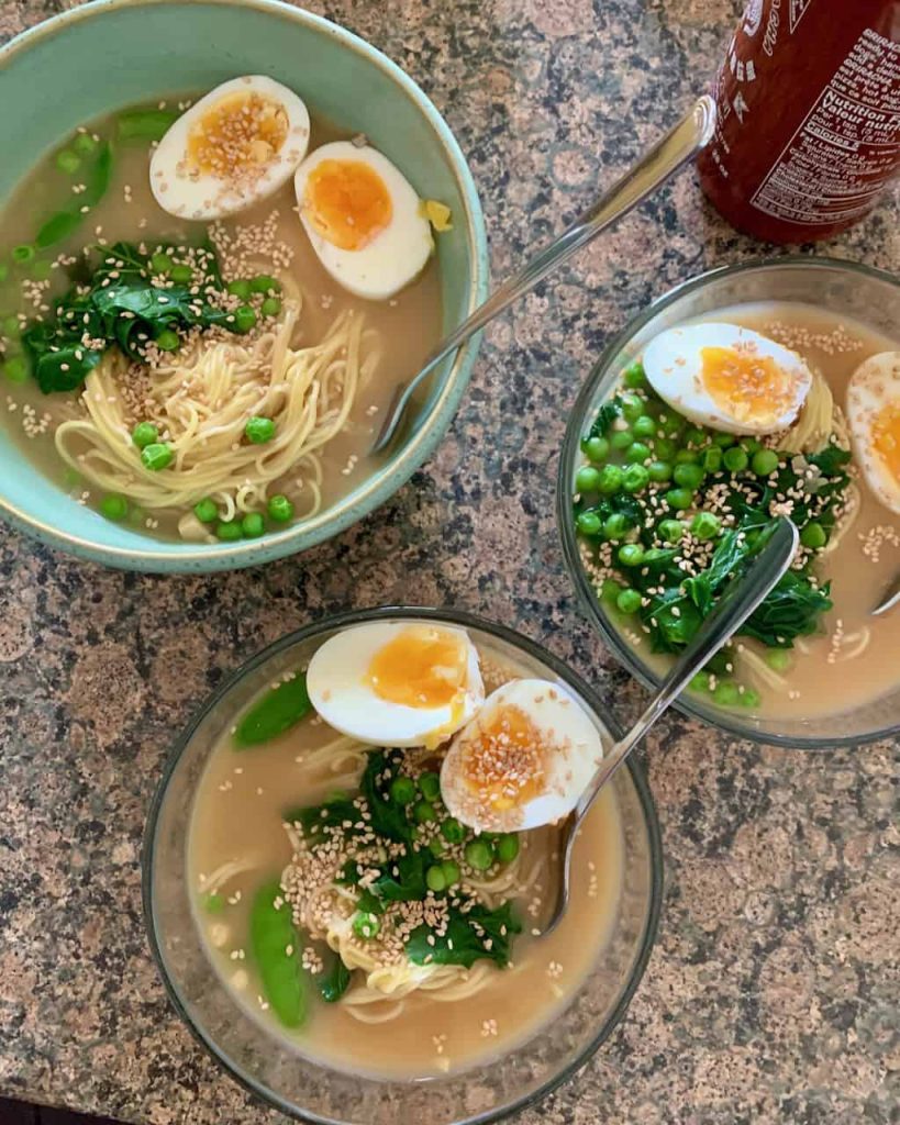 3 bowls of noodle soup with a jammy egg on top of each bowl.