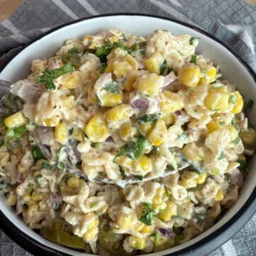 a spoonful of elote pasta salad over a white bowl.