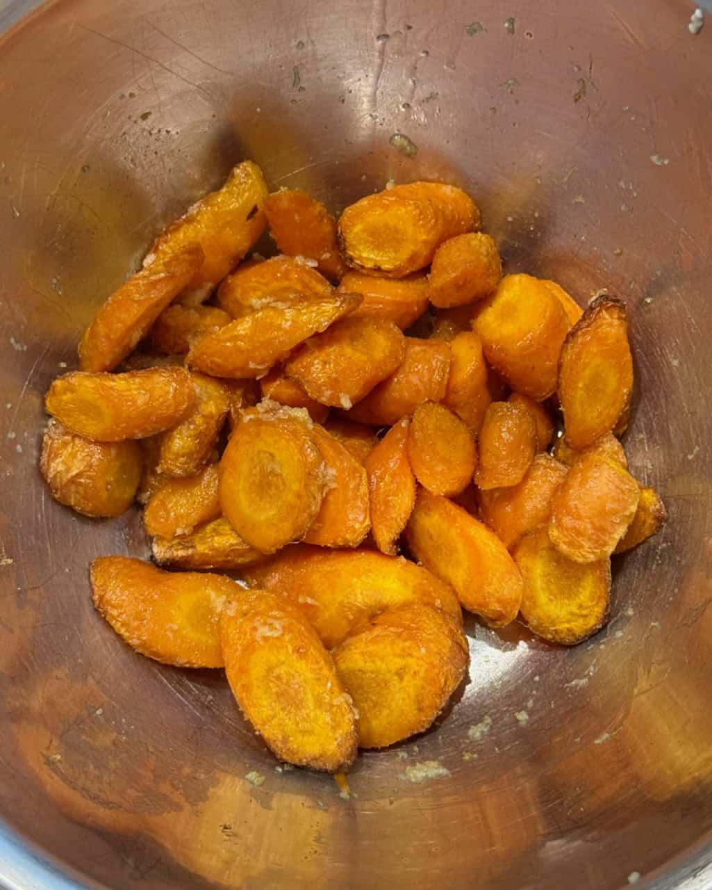 Close-up of roasted carrot slices in a metal bowl, ready to be blended in to a dip.