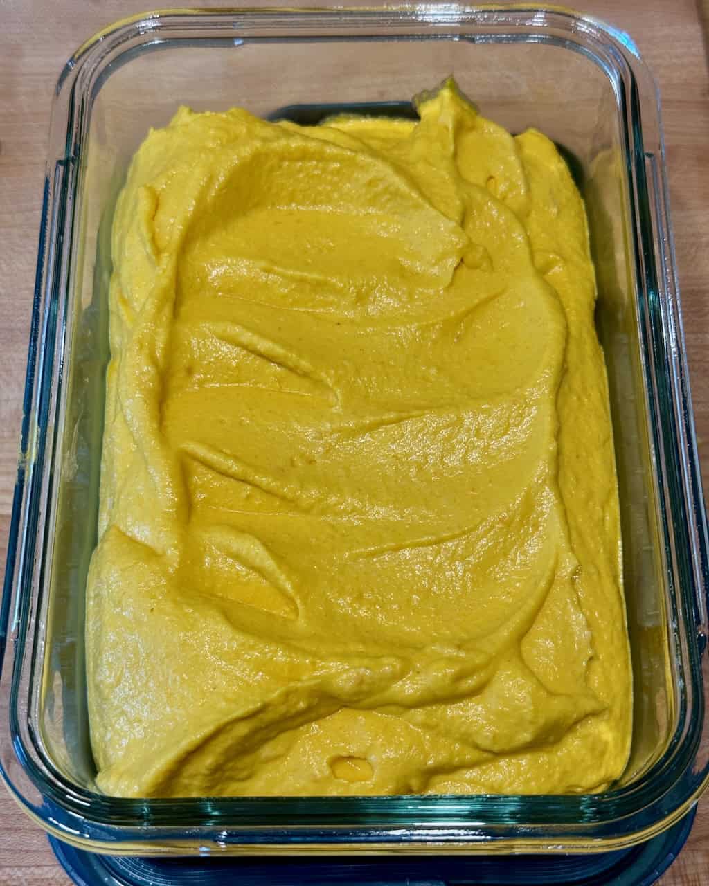 Creamy yellow roasted carrot dip in a glass dish for dinner.