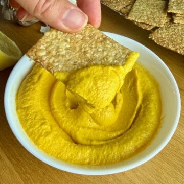 Creamy roasted carrot dip with crispy crackers for a healthy snack.
