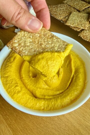 Creamy roasted carrot dip with crispy crackers for a healthy snack.