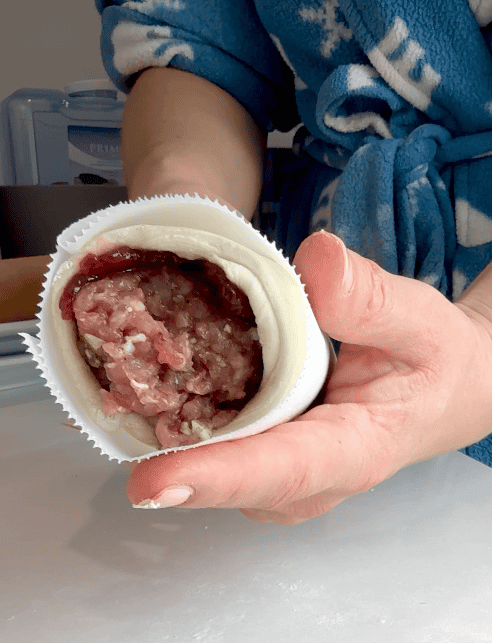 The sausage log rolled up in parchment paper.