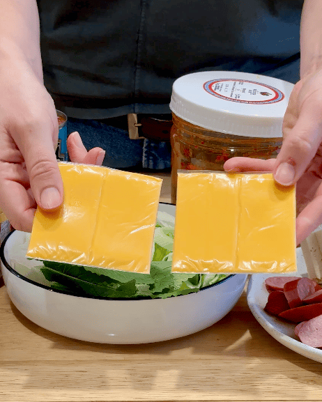 A woman holds two pieces of processed cheese.