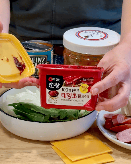 A woman holds a container of gochujang.