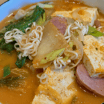 Korean Army Stew (Budae Jjigae) with noodles, tofu, sausage, and vegetables. Easy 10-minute meal ins.
