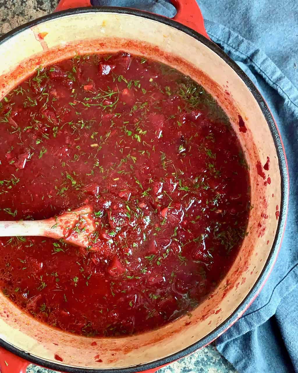 Finished beet soup in pot with a wooden spoon.