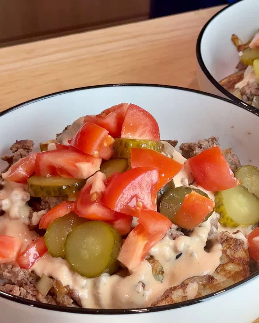 Adding tomatoes to the cheeseburger bowl.