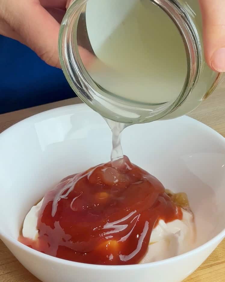 A woman adds pickle juice to the burger sauce.
