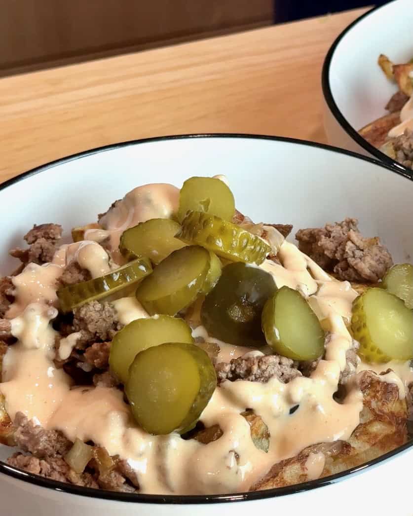 Adding pickles to the cheeseburger bowl.