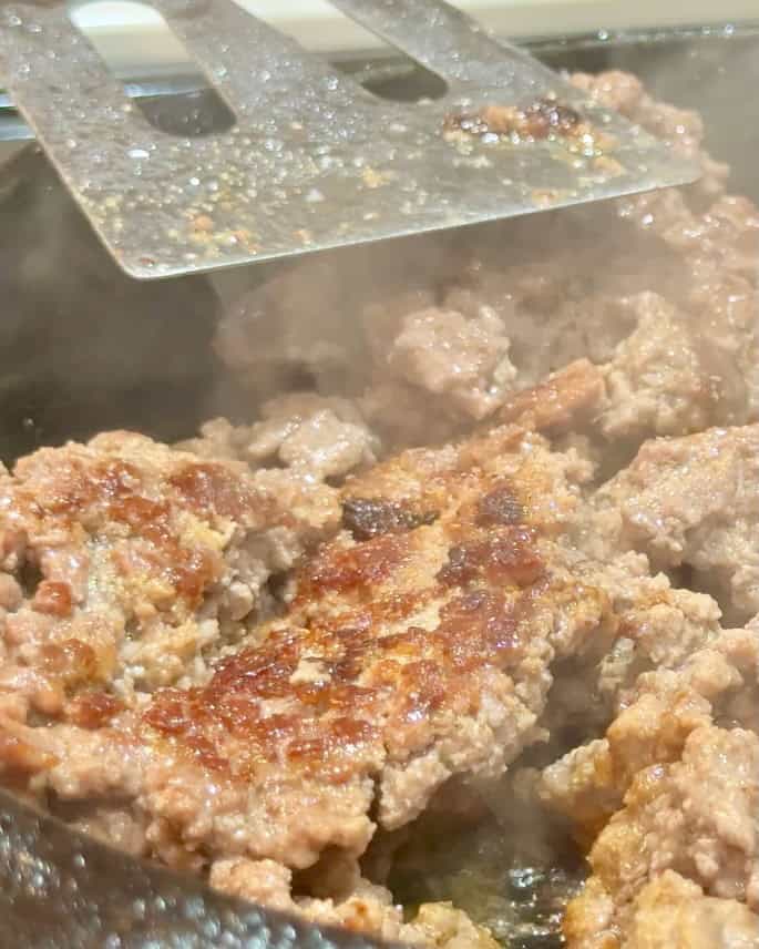 Browning the ground beef in a cast iron pan.