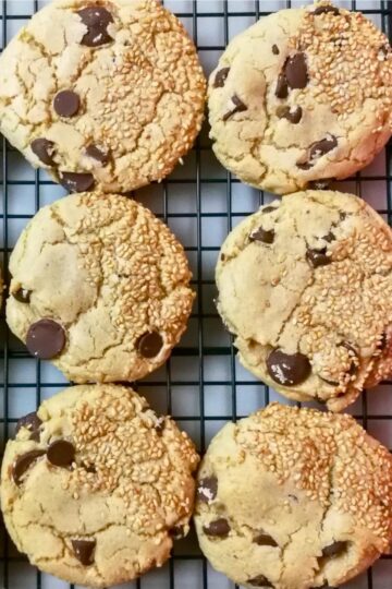 A batch of chocolate chip tahini cookies laid out on a cooling rack.