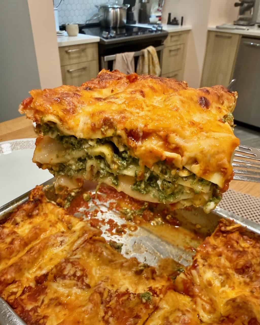 A slice of lasagna with a kitchen background.