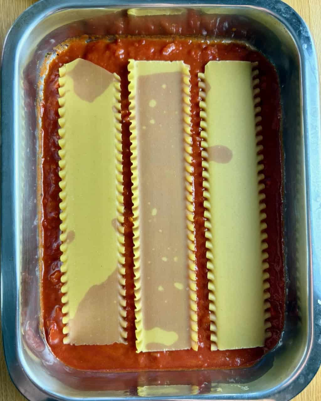 Layering the lasagna - sauce & noodles.