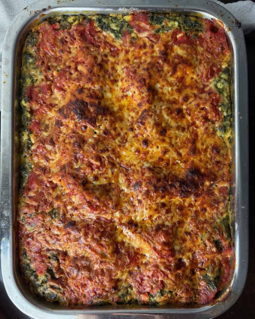 A fully baked, brown and bubbly lasagna cooling.