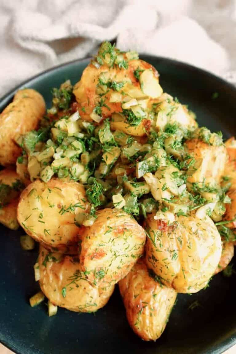 Crispy dill roasted potatoes on a plate, with one close-up on a fork.