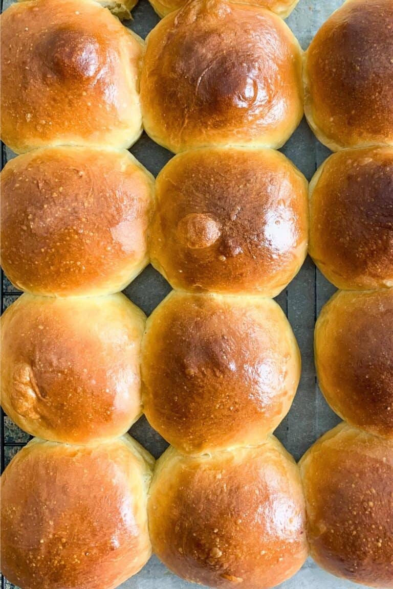 A batch of dinner rolls on a cooling rack.