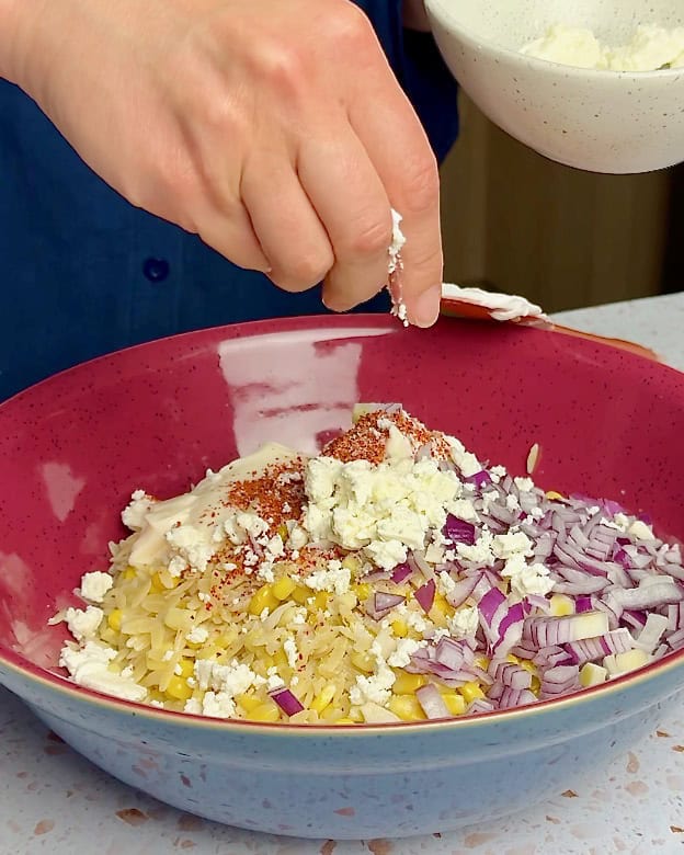 Adding the dressing ingredients to the corn and pasta.