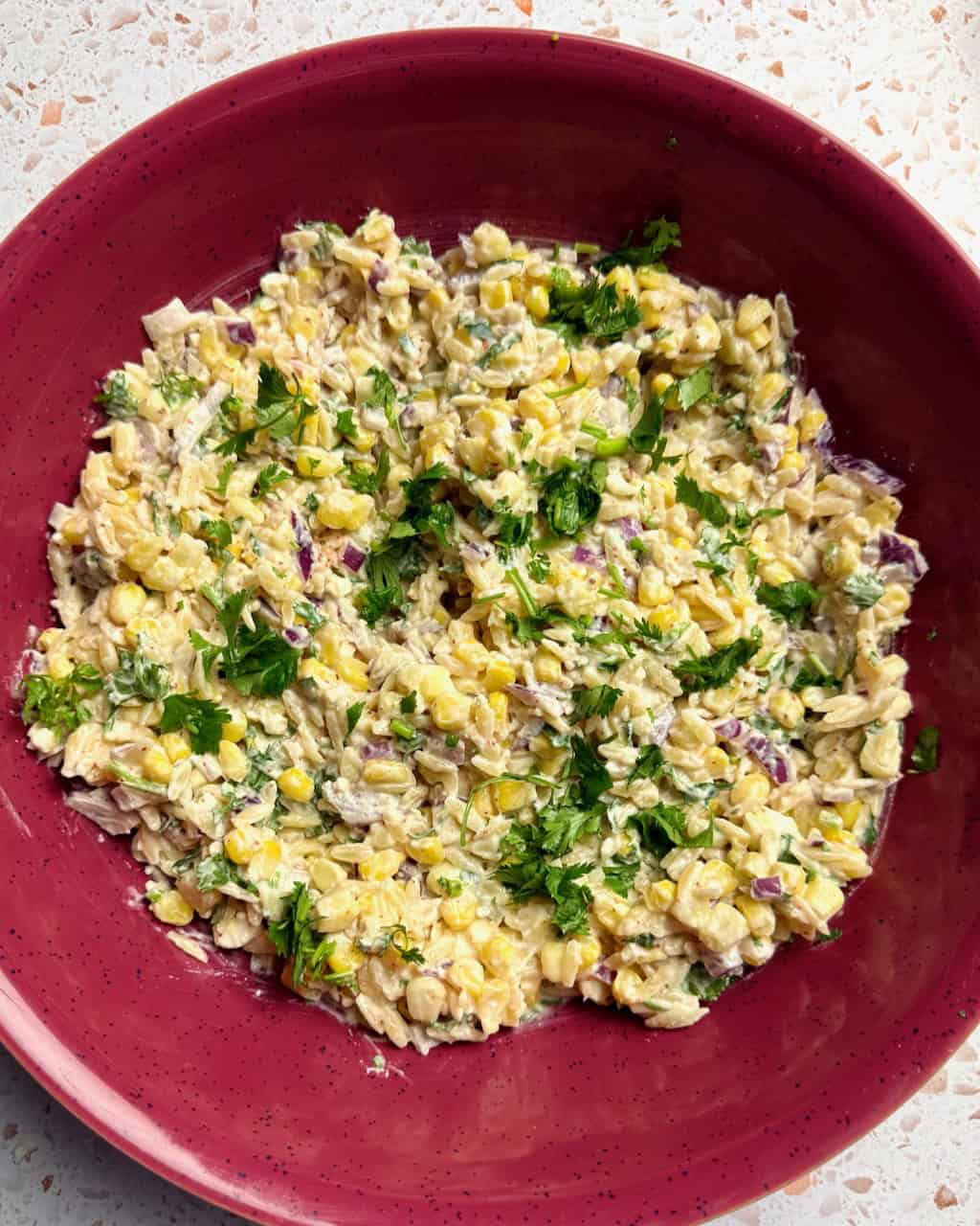 Elote pasta salad in a large red bowl.