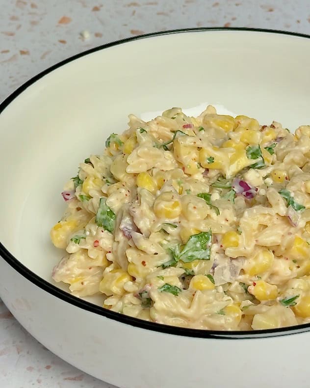 A white bowl with elote pasta salad.