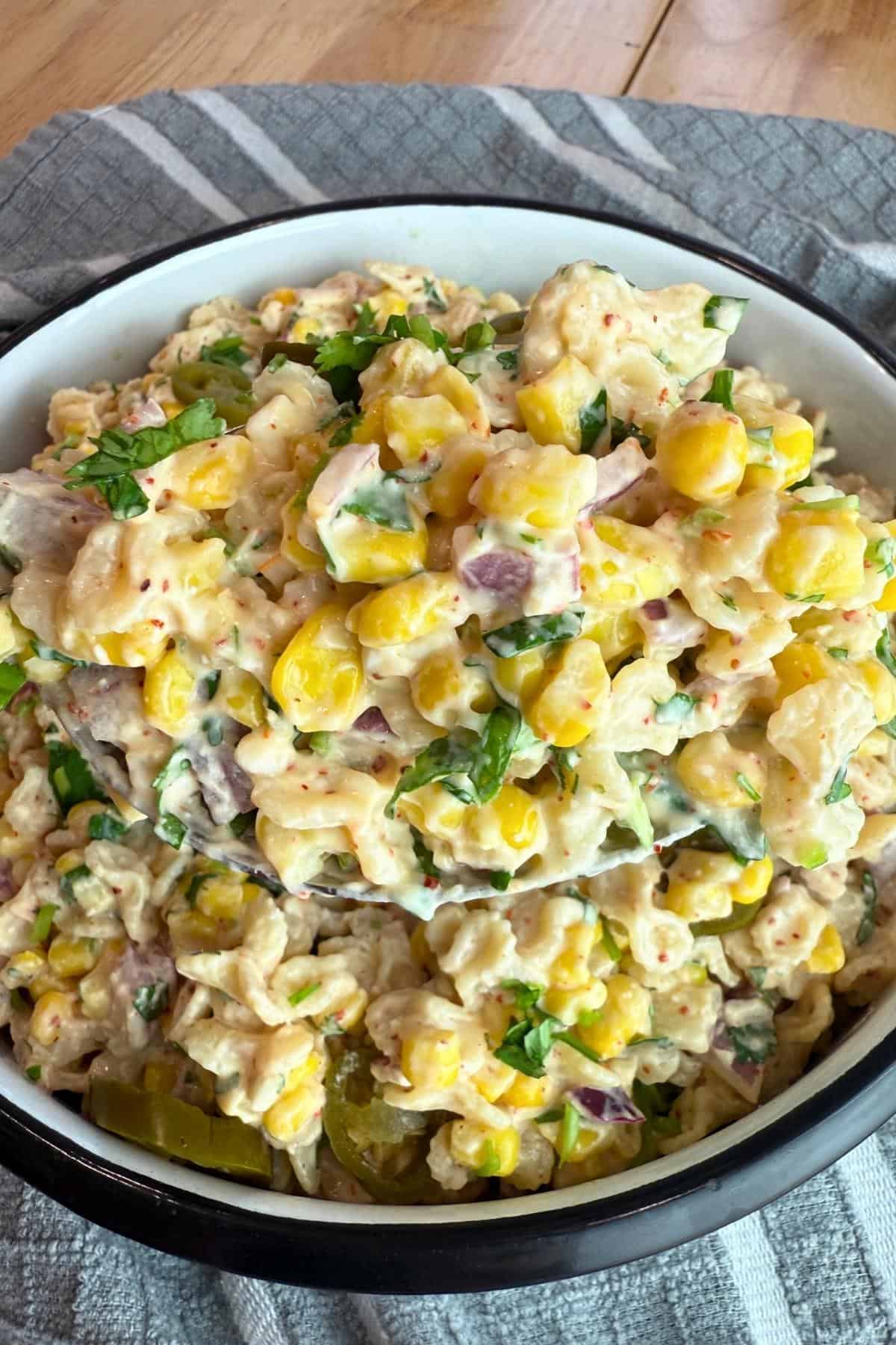 a spoonful of elote pasta salad over a white bowl.