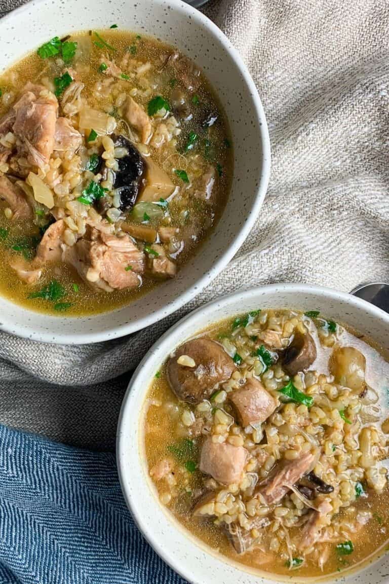 Two bowls of chicken and brown rice on a table.