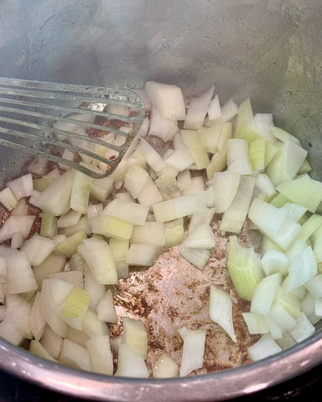 Adding chopped onions to the Instant Pot to soften.