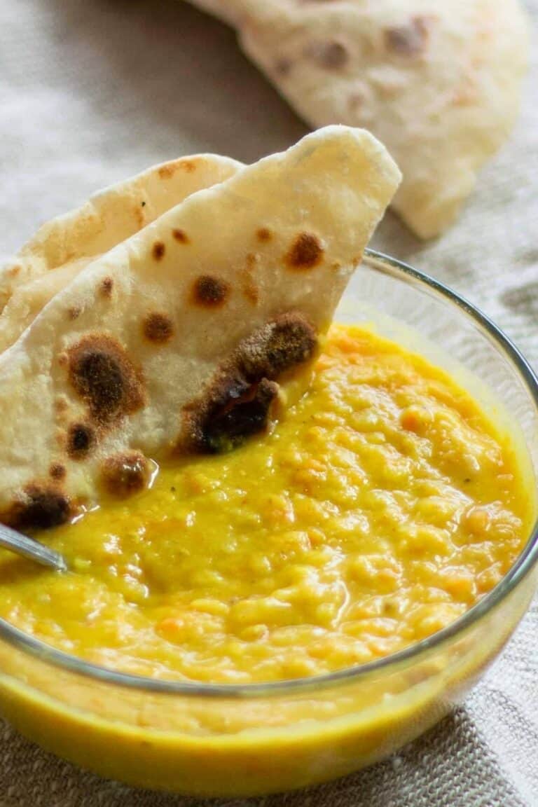 A bowl of carrot ginger lentil soup with a side of flatbread.