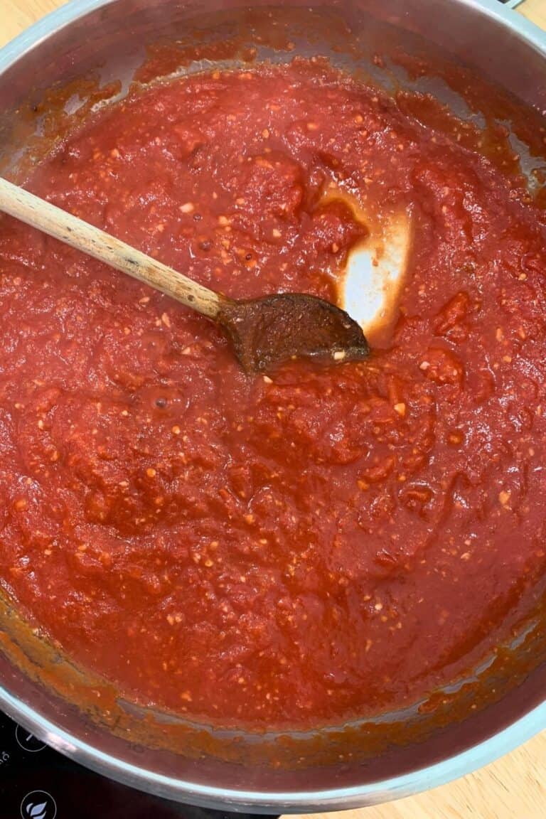 A pan of hearty marinara sauce with a wooden spoon.