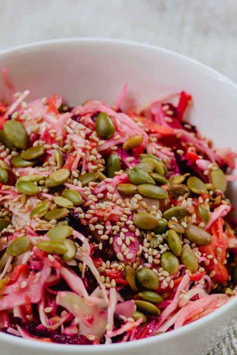 Veggie slaw with miso sesame dressing in a white bowl.