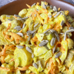 Classic potato salad in a brown bowl on a blue table with a grey napkin.