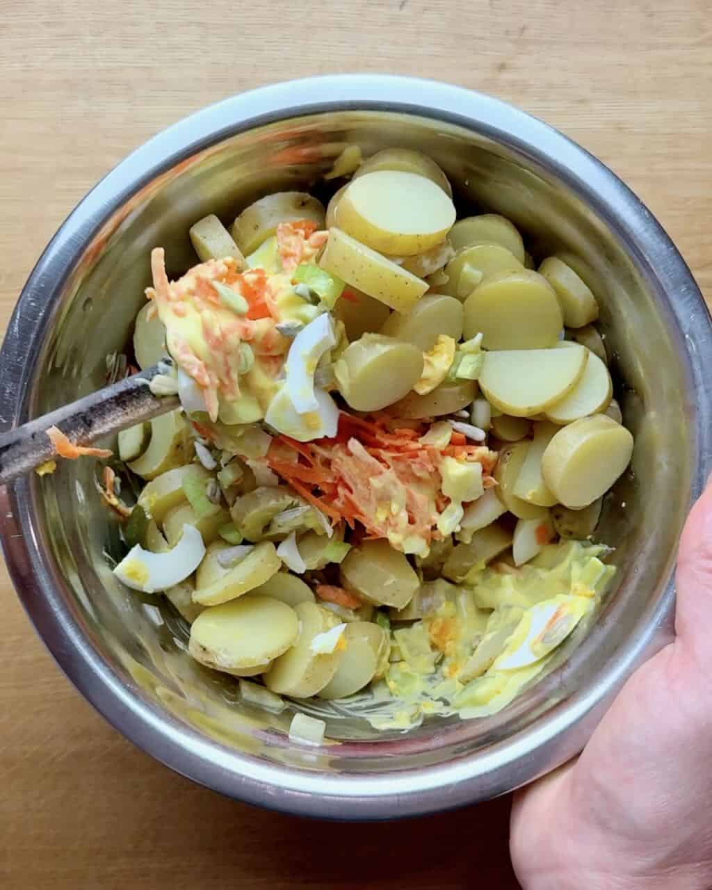 Stirring the potatoes into the salad.