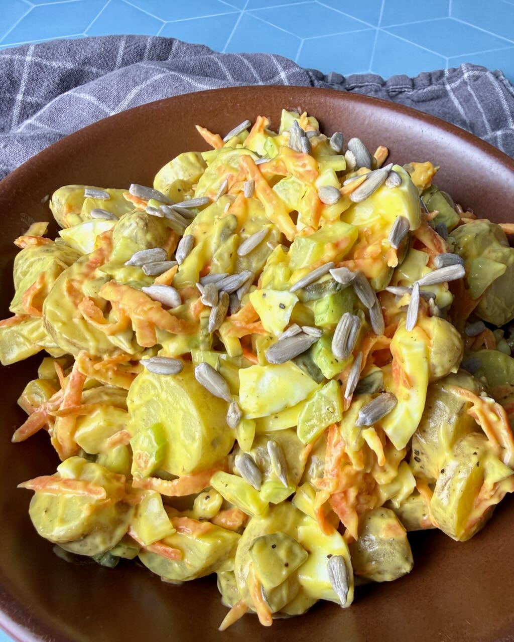Classic potato salad in a brown bowl on a blue table.