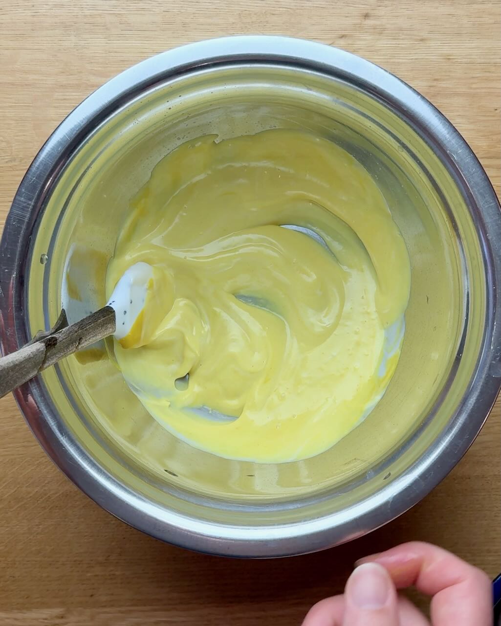 A stainless steel bowl with potato salad dressing.