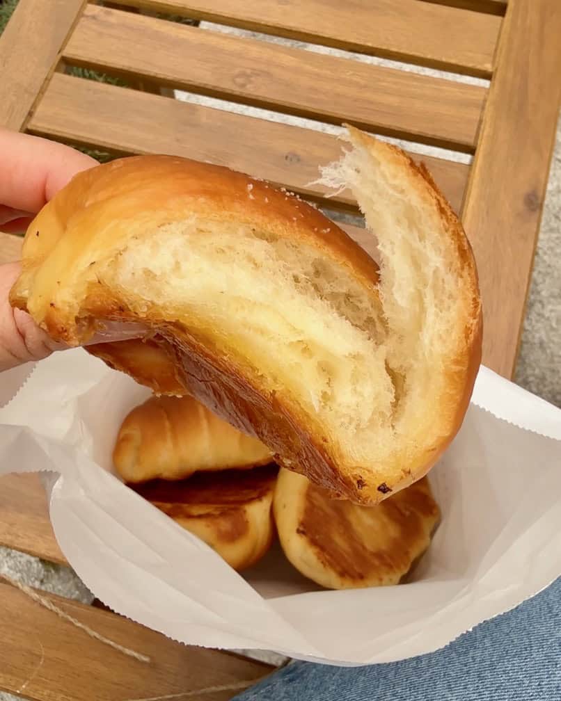 A woman holds a buttery salt bread roll.