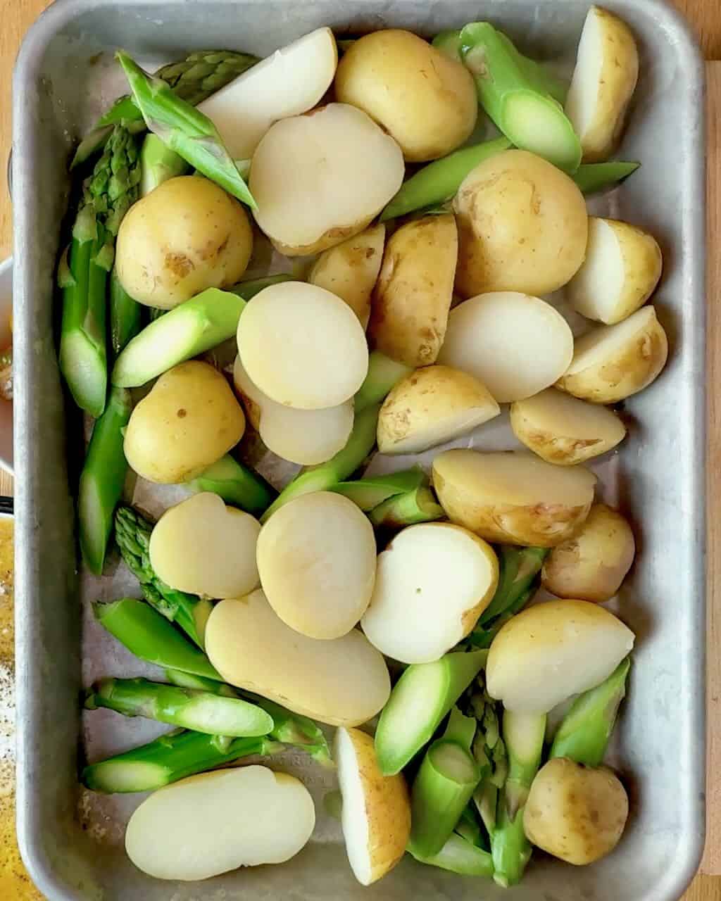 Boiled potatoes and asparagus cooling on a baking sheet.
