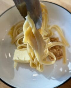 Tossing the pasta with the nutritional yeast, miso, butter mixture.
