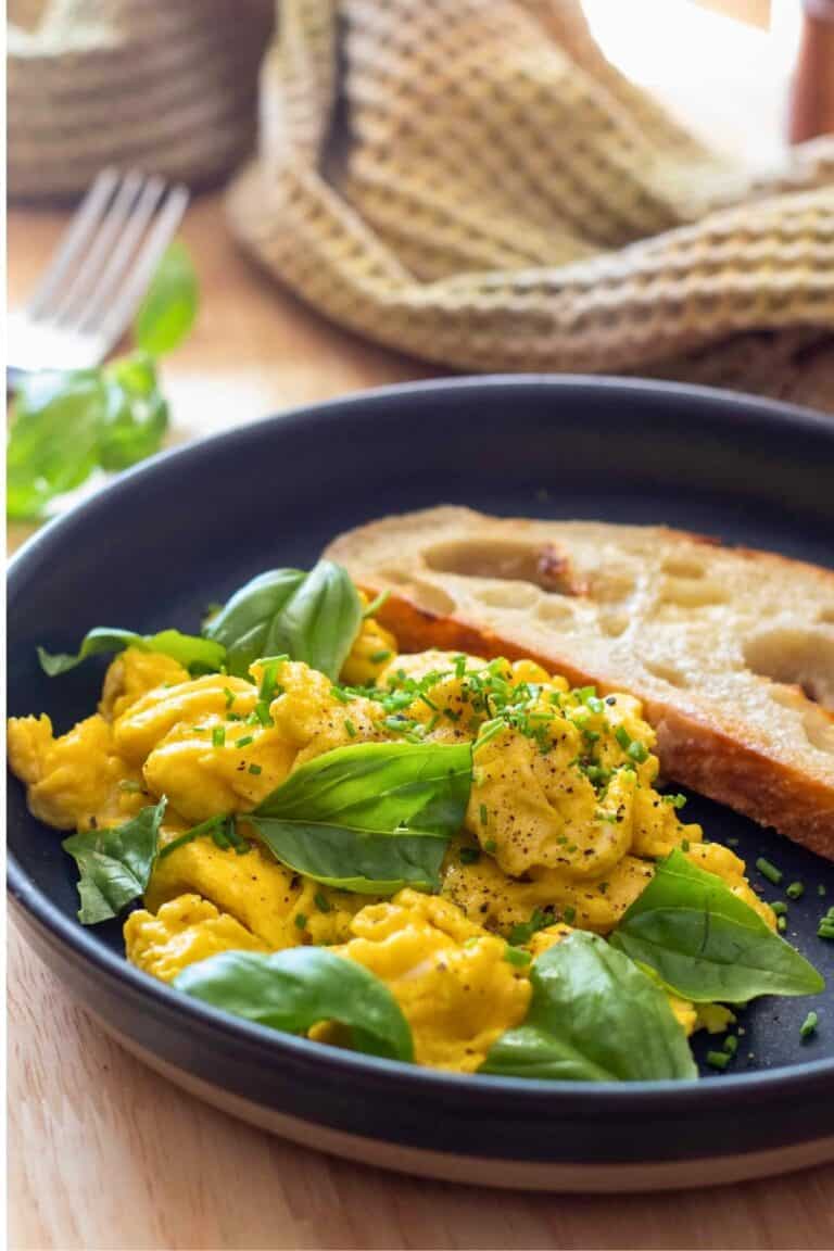 scrambled eggs with fresh herbs and toast on a plate.