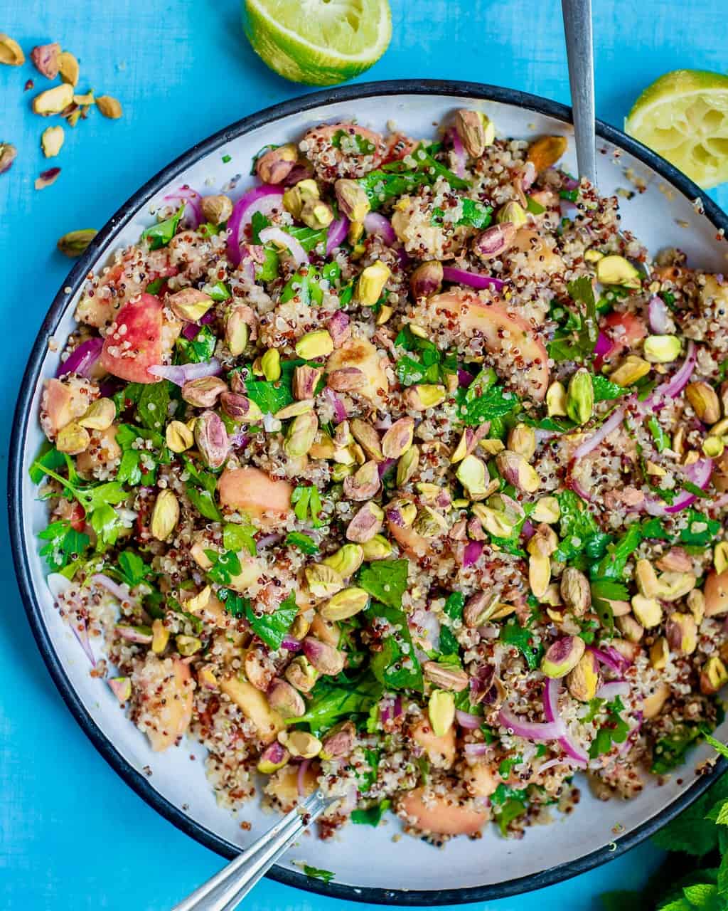 a bowl of peach quinoa salad on a blue table.