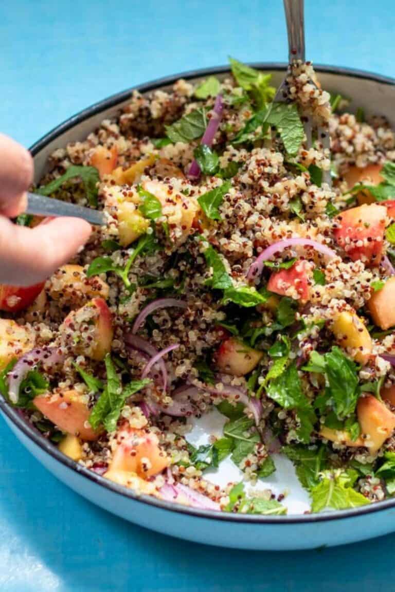 a bowl of peach quinoa salad on a blue table.