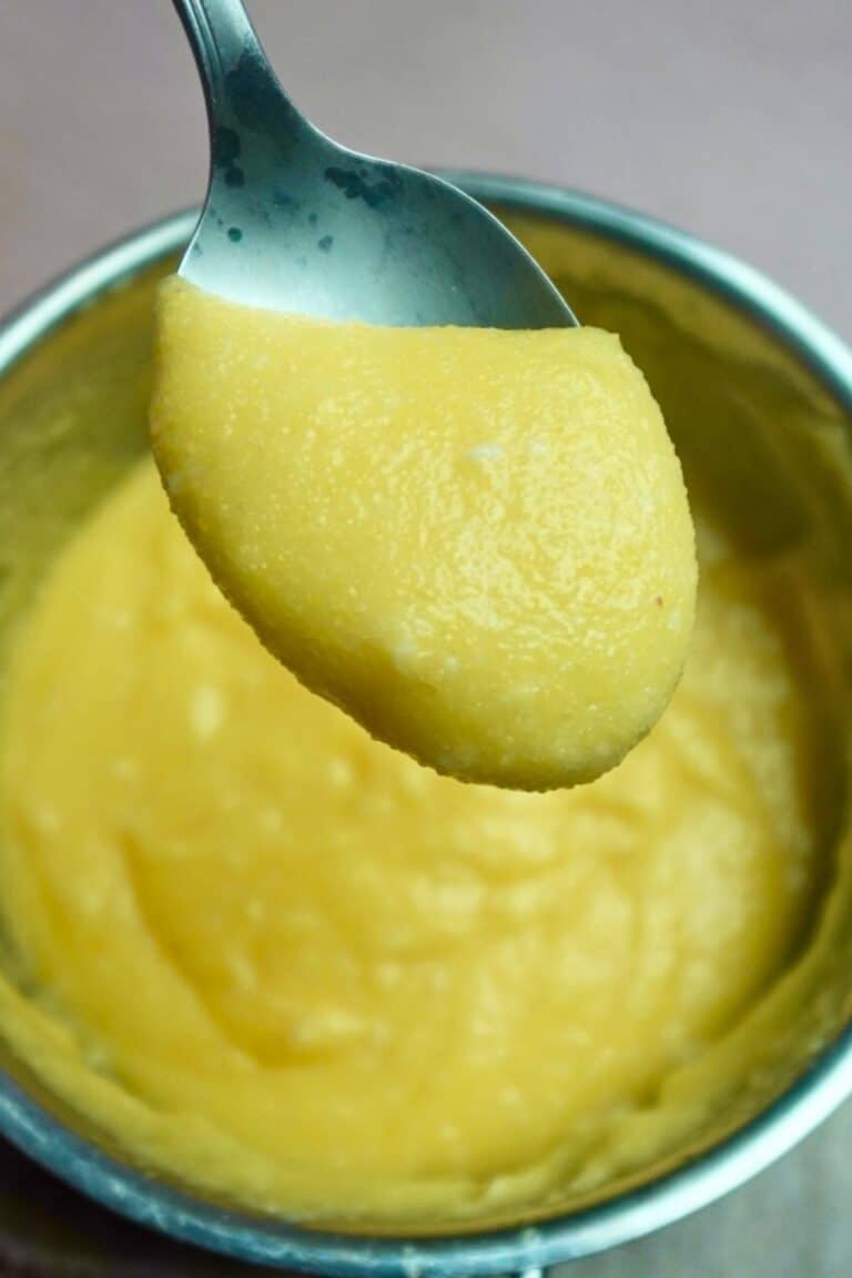 A spoon of soft polenta cooked on the stovetop.