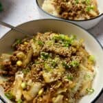 two bowls of pork and cabbage stir fry.