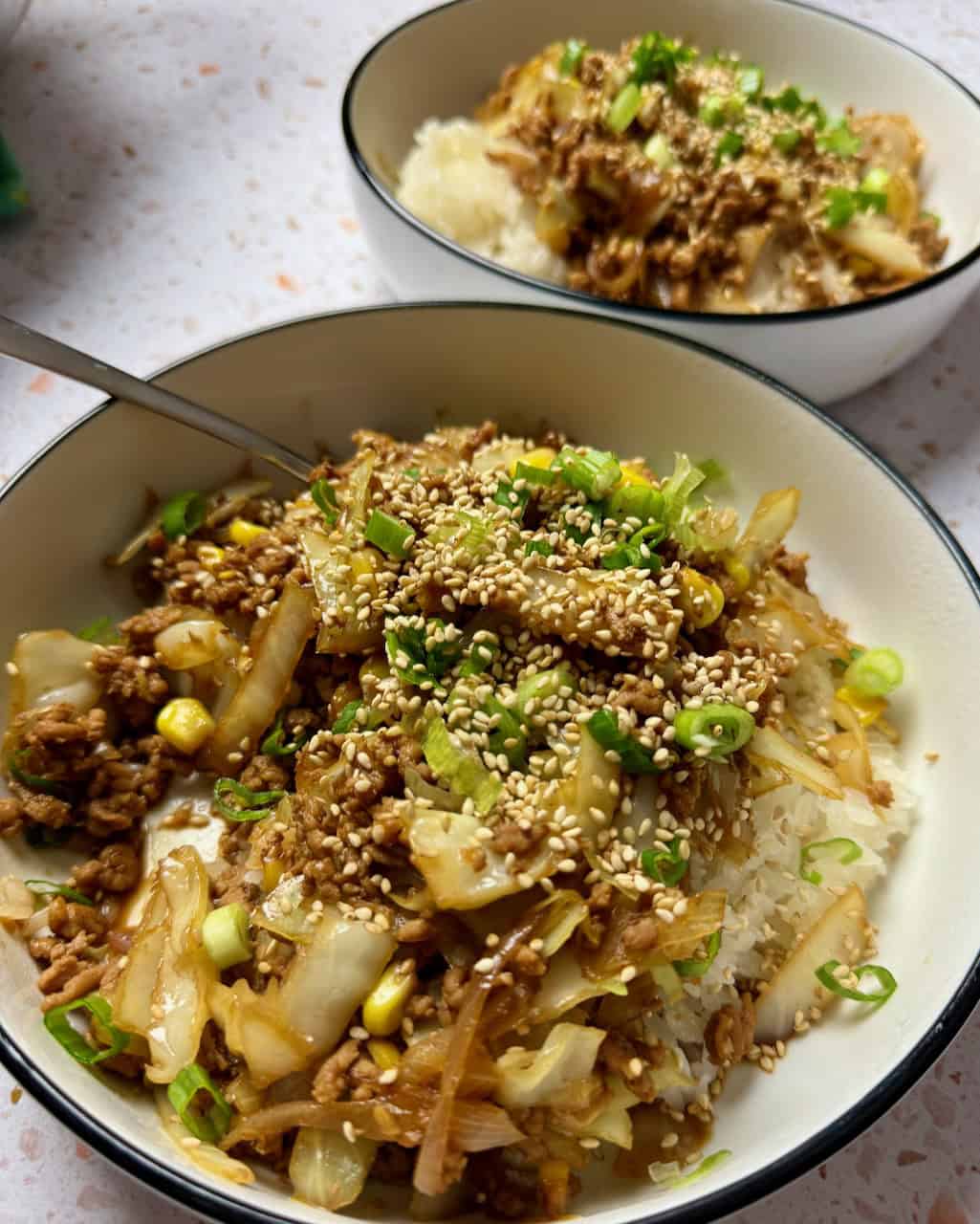 two bowls of pork and cabbage stir fry.