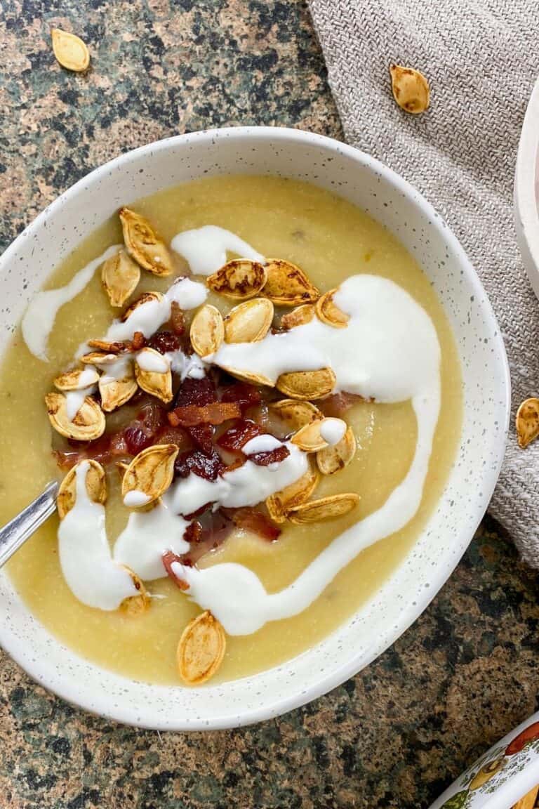 Rutabaga soup with crispy bacon, sour cream, and pumpkin seeds in a bowl.