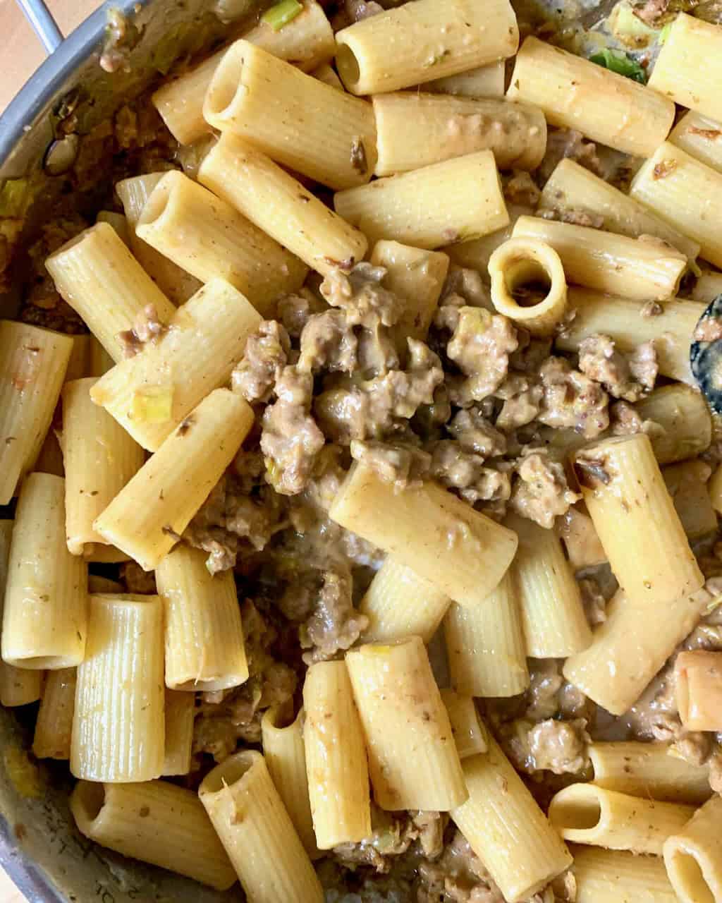 Closeup of creamy sausage and leek pasta in a pan.