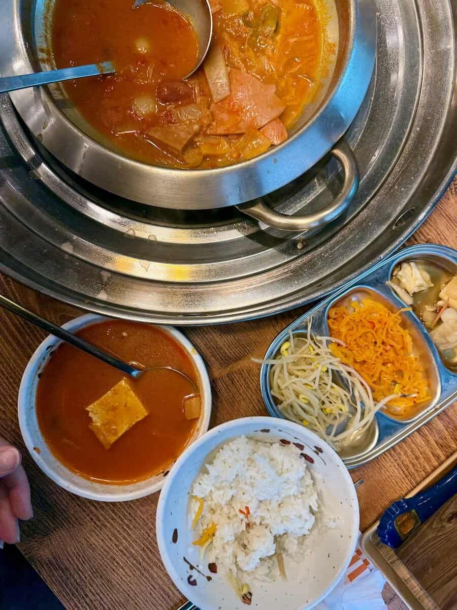 A pot of Korean Army Stew with side dishes.
