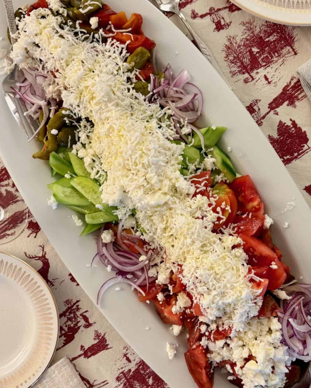 A big platter of Shopska salad on a patterned tablecloth.